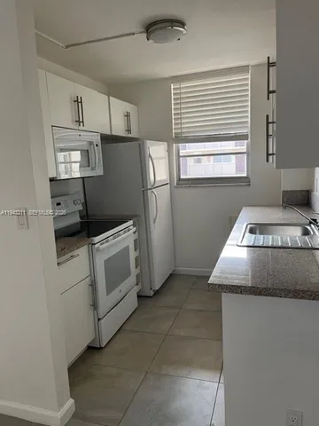 a kitchen with white cabinets and white appliances