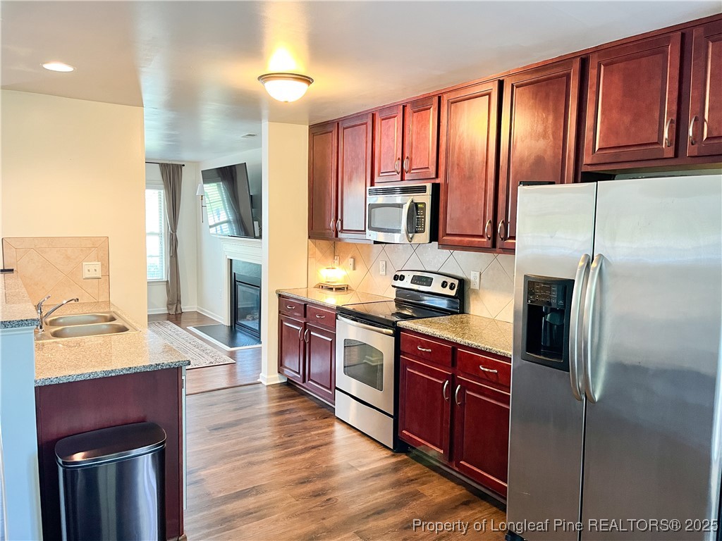 52 Expedition Drive Cameron, NC 28326 - Photo 5 of 14 a kitchen with stainless steel appliances granite countertop a refrigerator a sink dishwasher a stove with wooden cabinets and floor