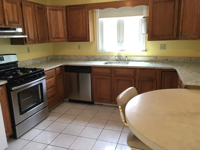 a kitchen with granite countertop a stove a sink and dishwasher wooden cabinets with granite countertops