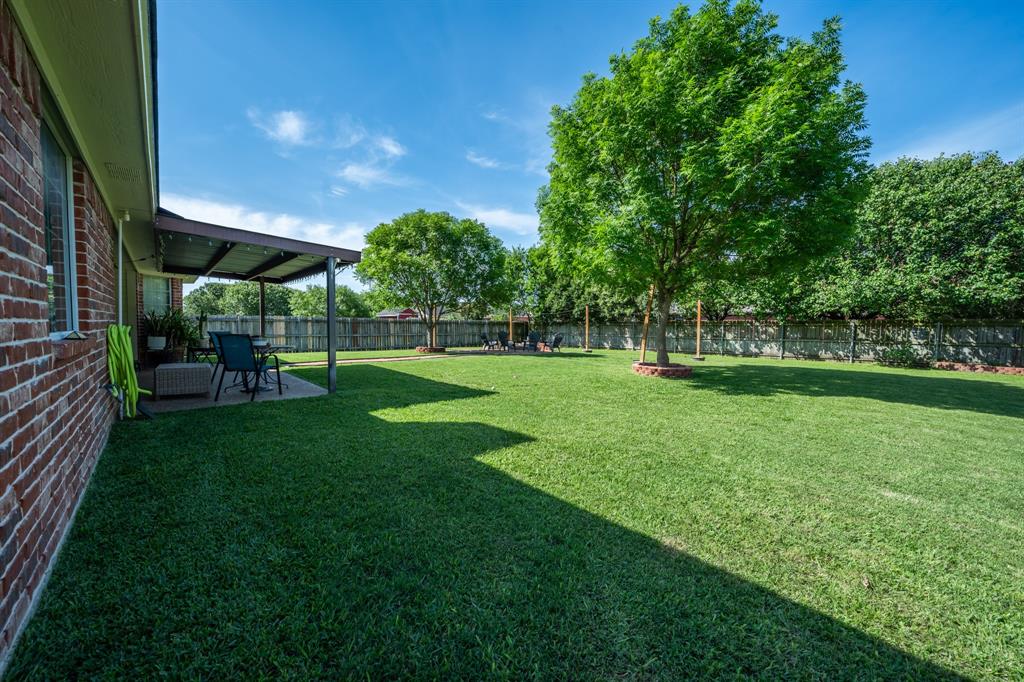10512 Whitney Trace Drive Waco, TX 76708 - Photo 7 of 39 Expansive backyard featuring a covered patio, mature shade trees, a full privacy fence, and a brick exterior