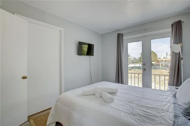 a bedroom with a bed and a flat tv screen next to a window