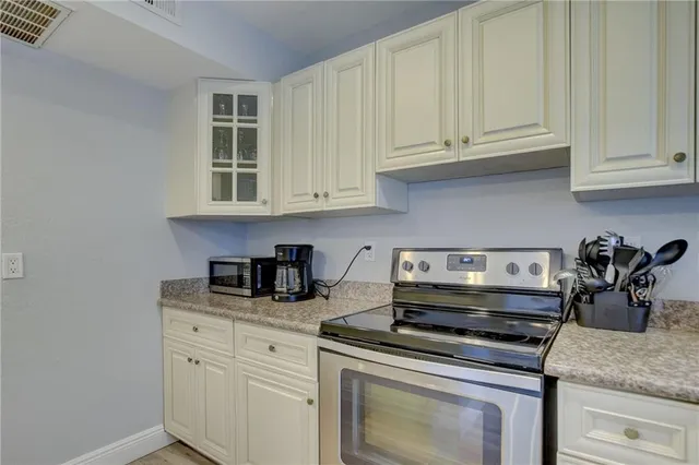 a kitchen with granite countertop white cabinets and a stove