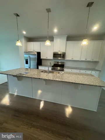 a large kitchen with a large counter top a sink stainless steel appliances and cabinets