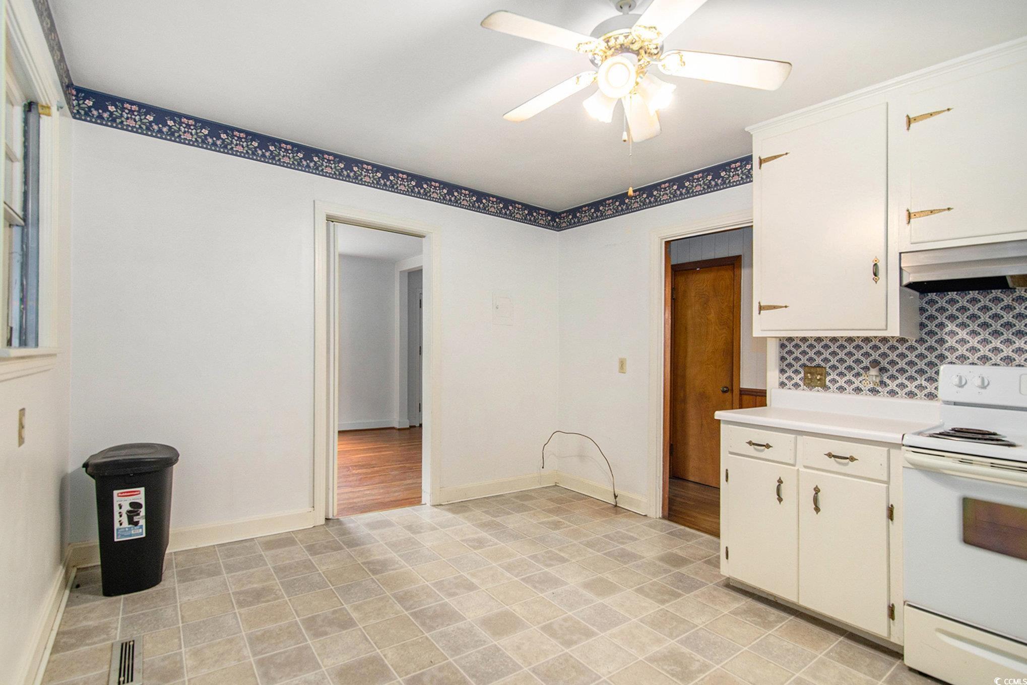1008 North Main Street Marion, SC 29571 - Photo 11 of 27 Kitchen with white electric range oven, light countertops, under cabinet range hood, ceiling fan, and white cabinetry