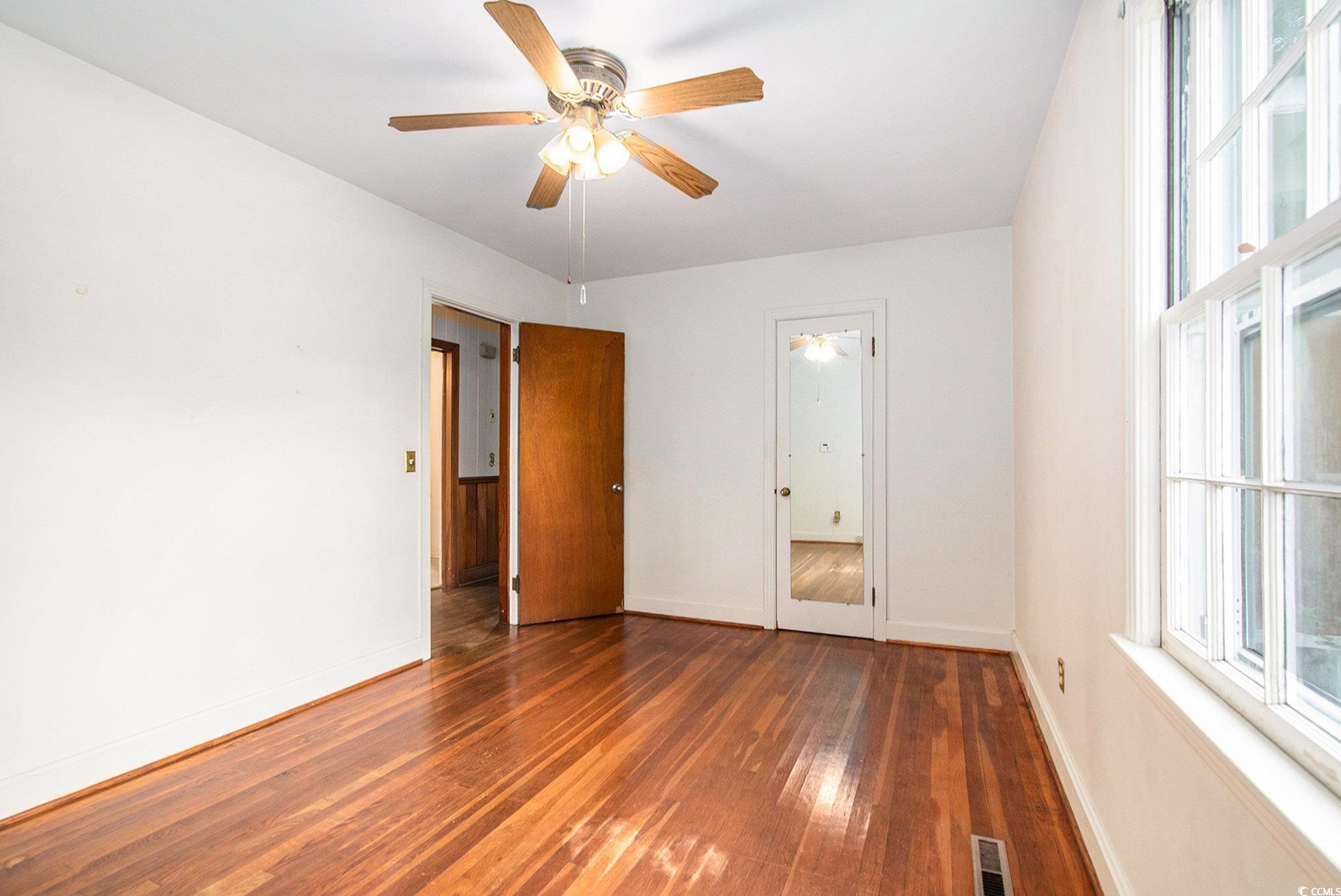 1008 North Main Street Marion, SC 29571 - Photo 15 of 27 Unfurnished bedroom featuring multiple windows, dark wood-style flooring, and ceiling fan