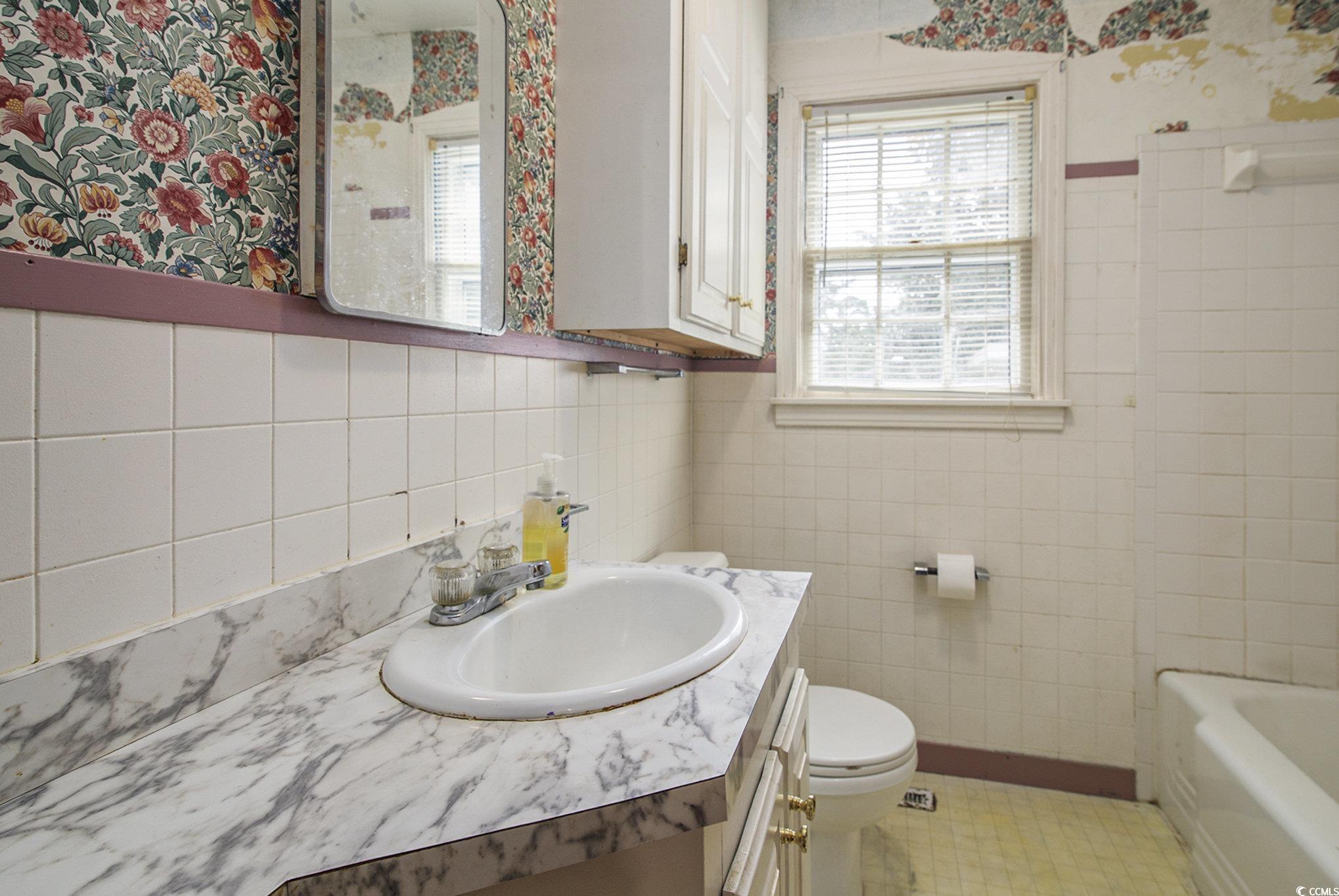 1008 North Main Street Marion, SC 29571 - Photo 16 of 27 Full bathroom with vanity, tile walls, shower / bath combination, and wallpapered walls
