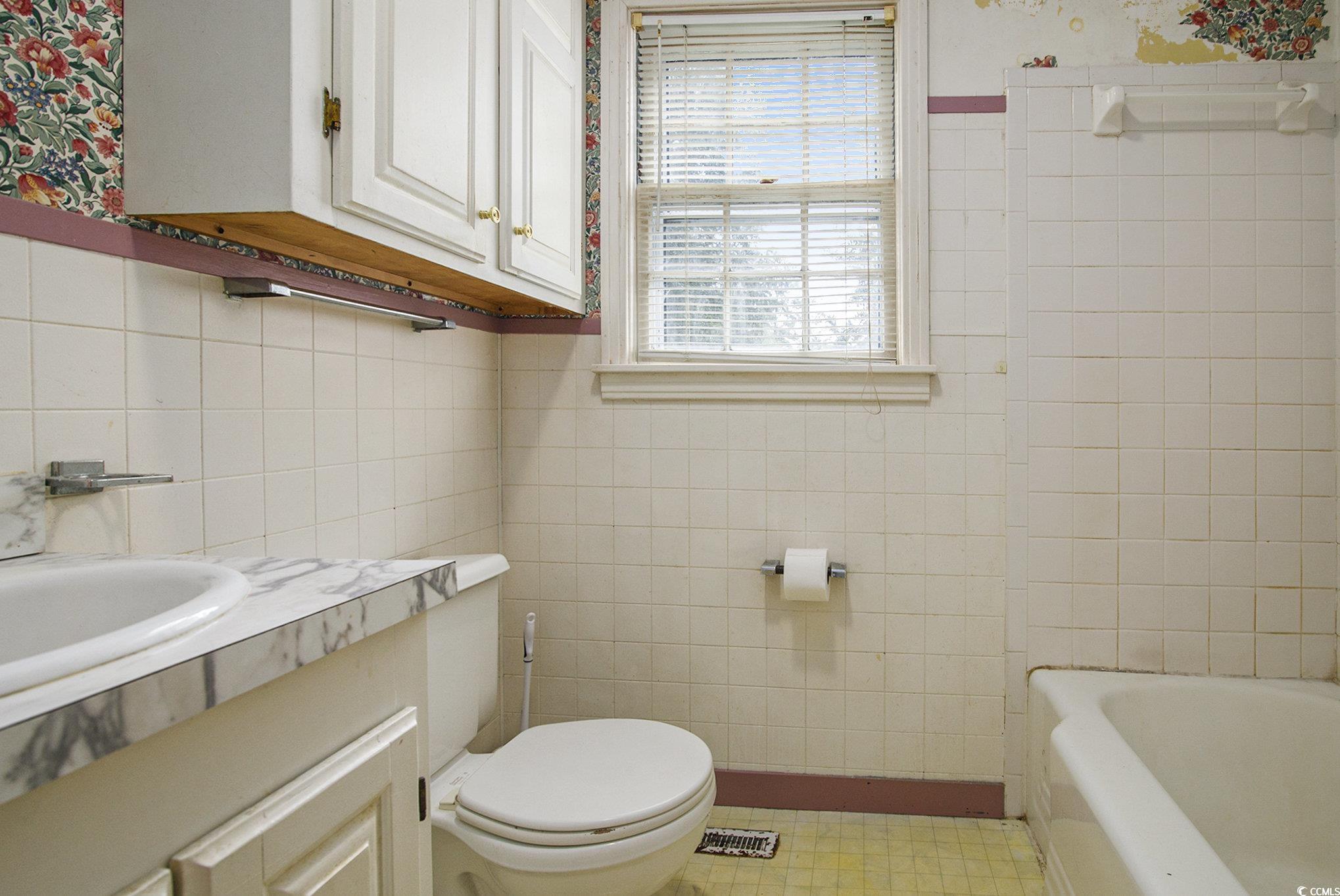 1008 North Main Street Marion, SC 29571 - Photo 17 of 27 Bathroom with tile walls, vanity, bathing tub / shower combination, and wallpapered walls