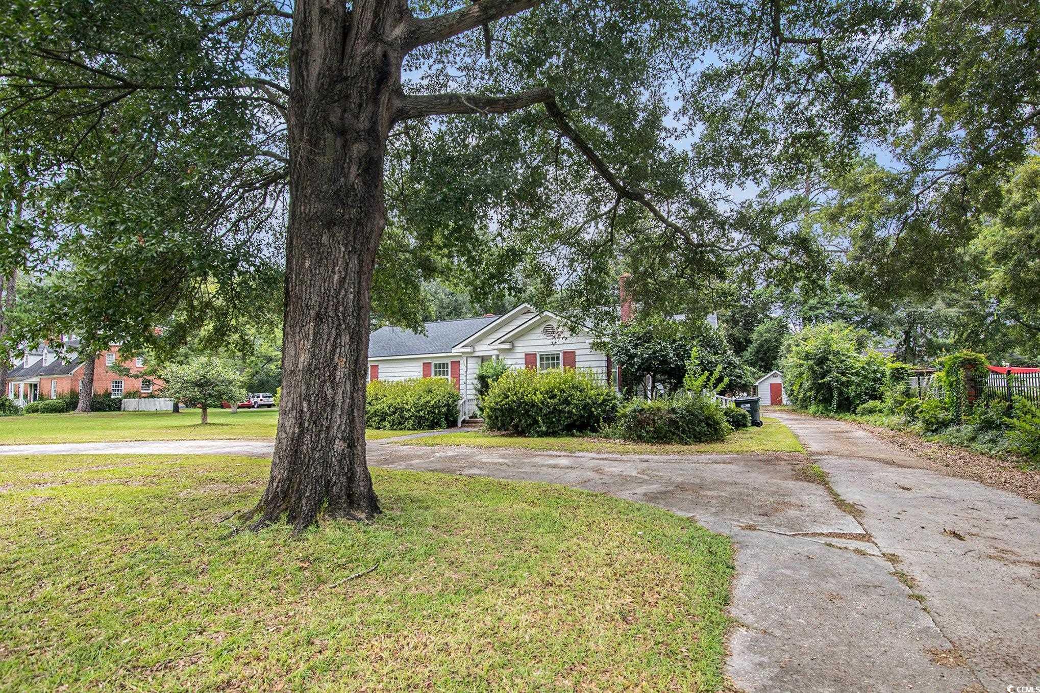 1008 North Main Street Marion, SC 29571 - Photo 3 of 27 Single story home with curved driveway, a front lawn, an outdoor structure, and view of scattered trees