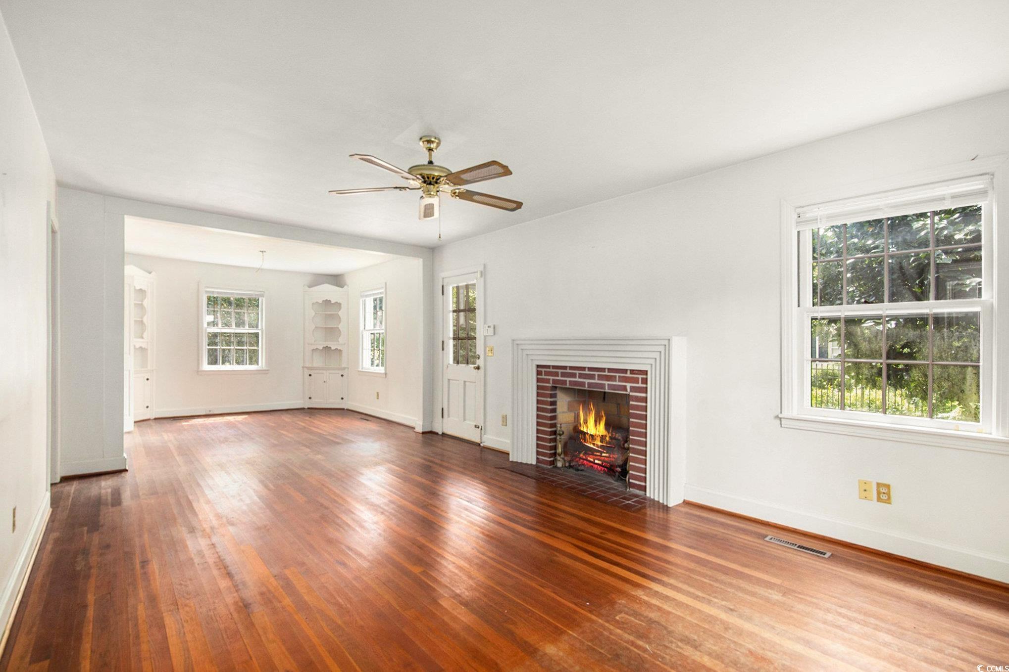 1008 North Main Street Marion, SC 29571 - Photo 6 of 27 Unfurnished living room with a brick fireplace, hardwood / wood-style floors, and ceiling fan