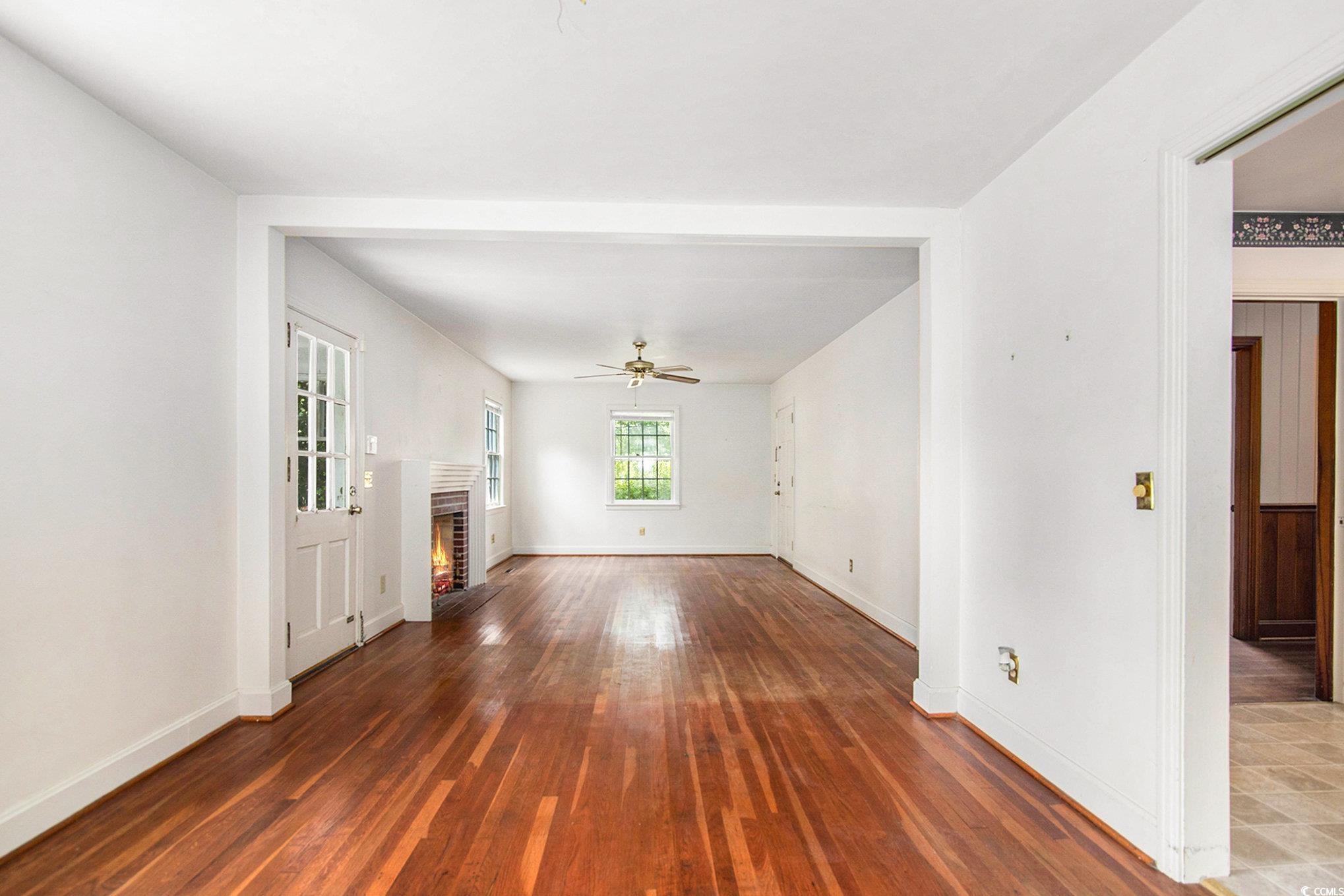 1008 North Main Street Marion, SC 29571 - Photo 8 of 27 Unfurnished living room featuring wood finished floors, ceiling fan, and a brick fireplace