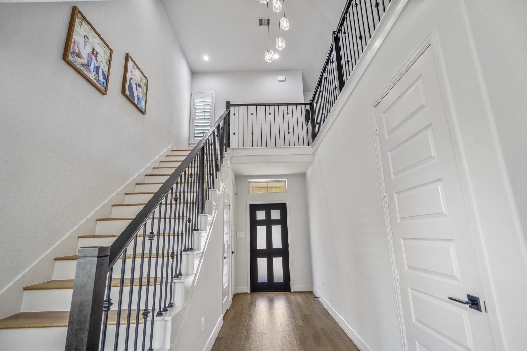 304 Mullins Court Montgomery, TX 77316 - Photo 20 of 50 This entryway showcases a bright, modern look with a high ceiling, elegant staircase with an upgraded black railing. The space is accented by LVP flooring and contemporary light fixtures, creating a welcoming and stylish first impression.