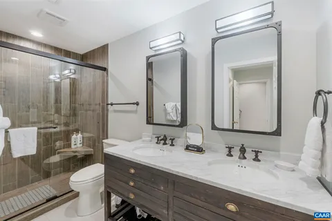 a bathroom with a double vanity sink toilet mirror and shower