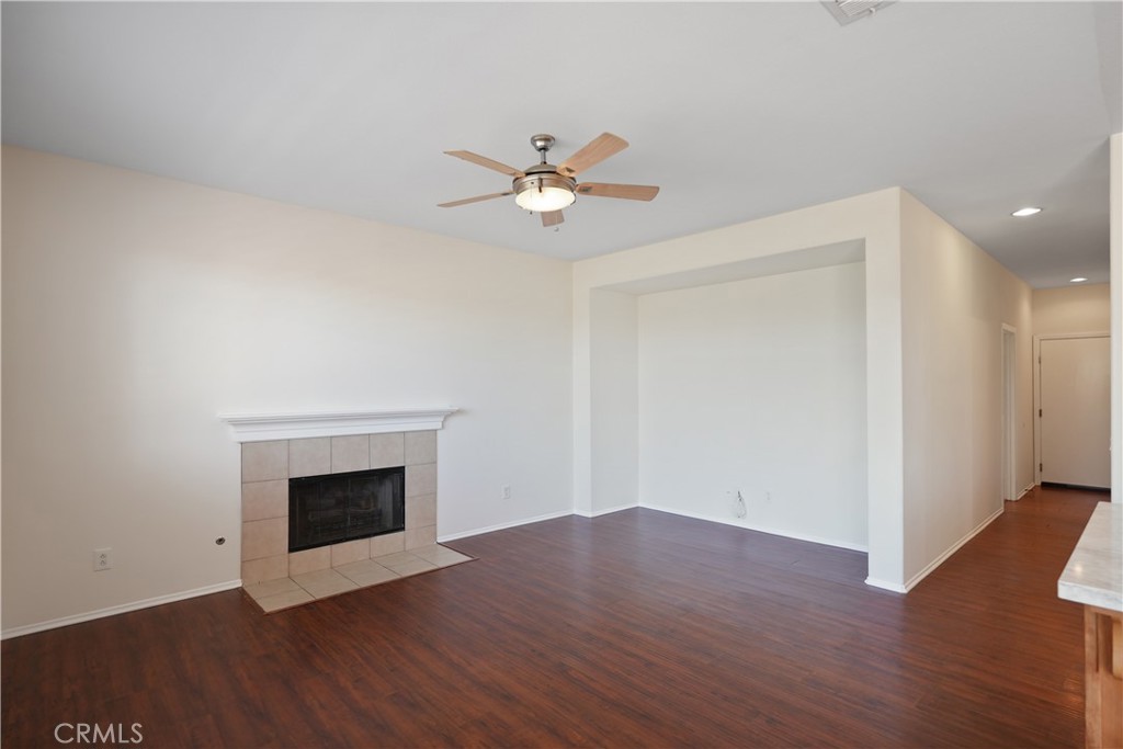 38815 Cobblestone Circle Murrieta, CA 92563 - Photo 14 of 49 an empty room with wooden floor a ceiling fan a fireplace and wooden floor