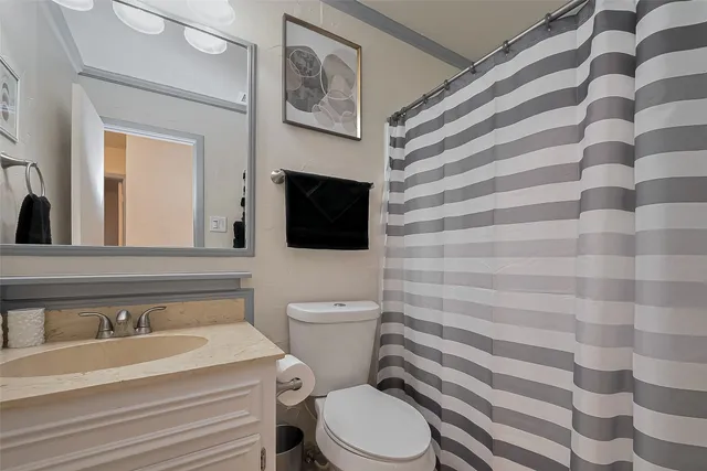 a bathroom with a granite countertop toilet sink and mirror