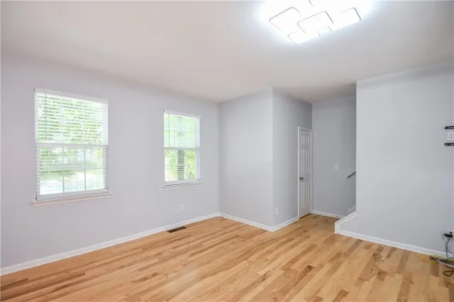 an empty room with wooden floor and windows