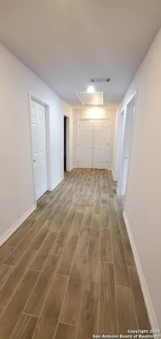 a view of an empty room with wooden floor and a bathroom