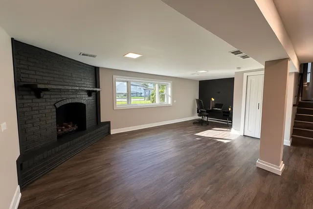 an empty room with fireplace and wooden floor