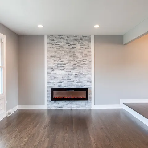 a view of an empty room with wooden floor and a fireplace