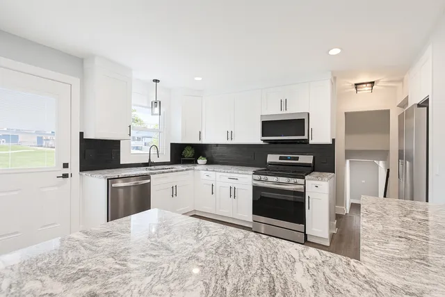 a kitchen with granite countertop a stove top oven and refrigerator