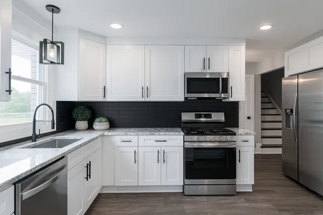 a kitchen with stainless steel appliances granite countertop a stove a sink and a microwave