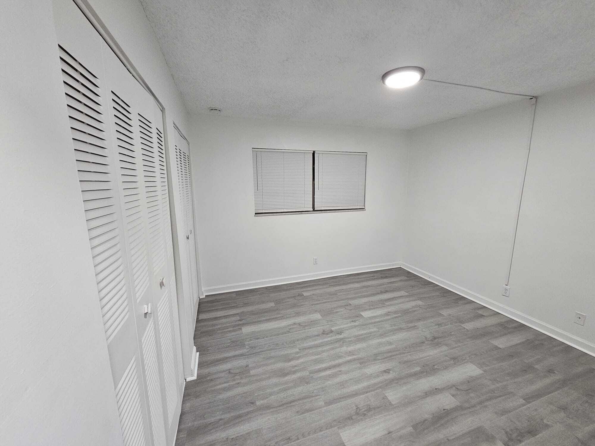 1853 Service Road North Palm Beach, FL 33408 - Photo 56 of 113 a view of an empty room with wooden floor and a window