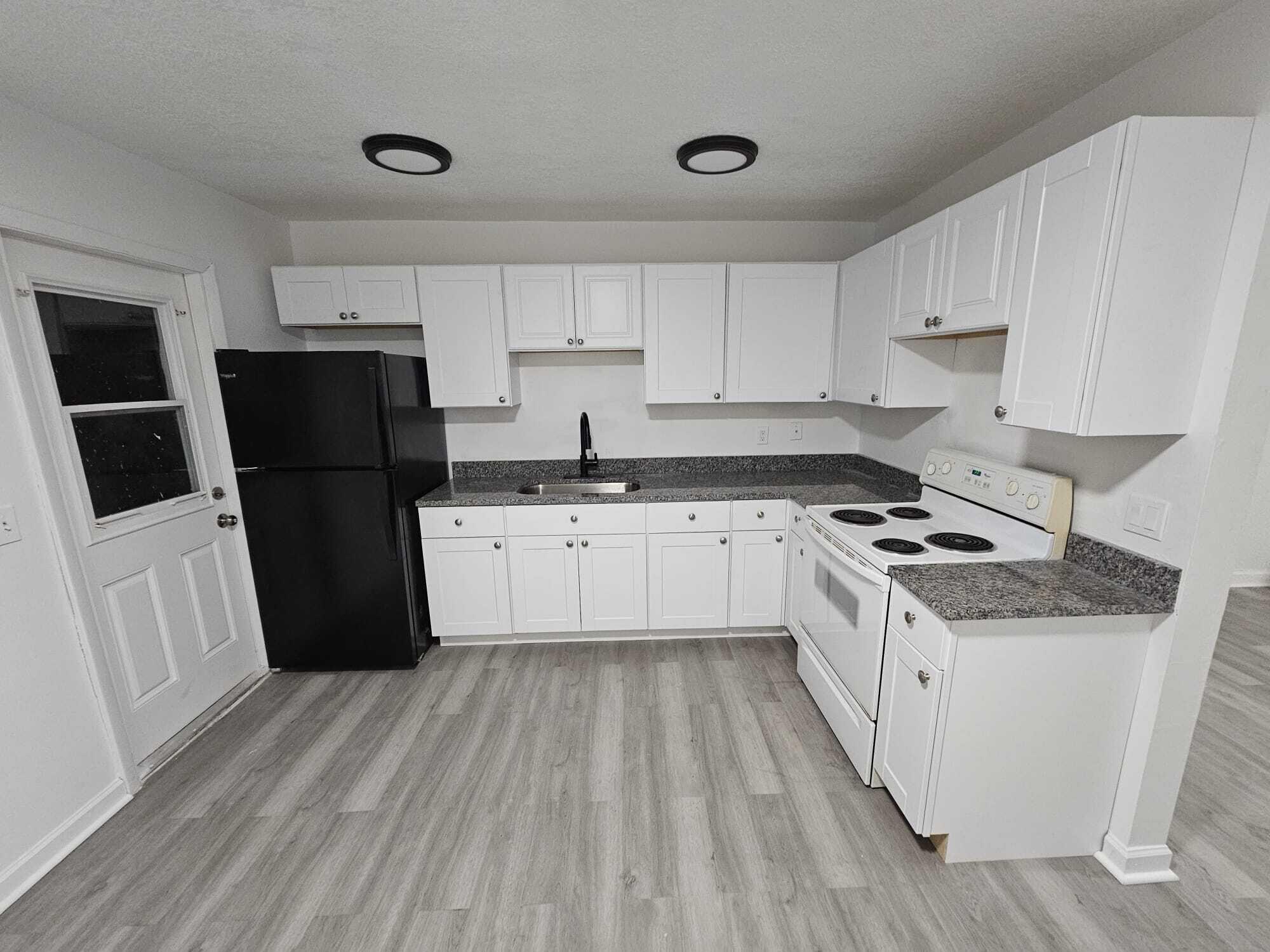 1853 Service Road North Palm Beach, FL 33408 - Photo 68 of 113 a kitchen with a sink a refrigerator a stove top oven and white cabinets