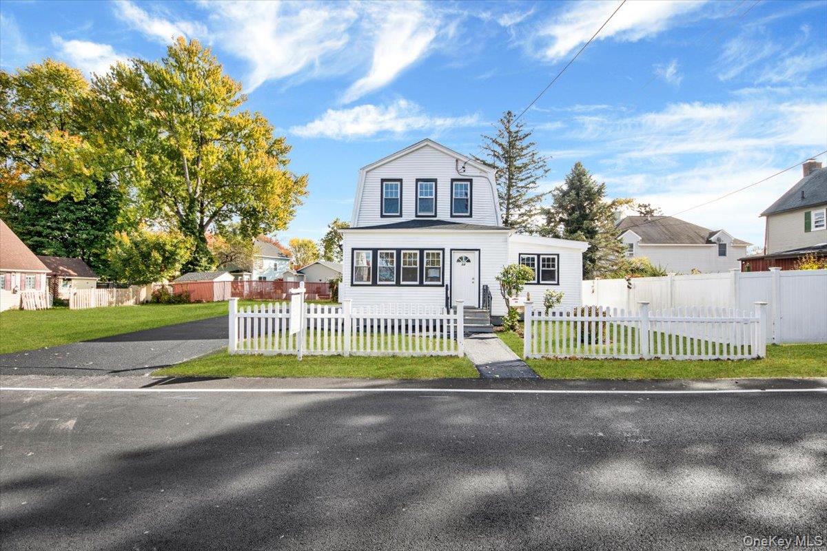 Dutch colonial with a fenced front yard, a gambrel roof, and driveway