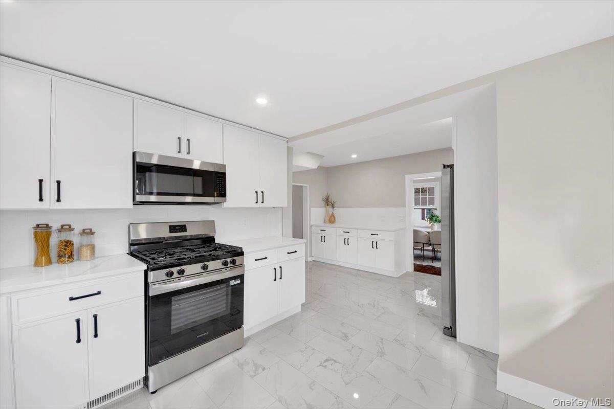 34 Kings Ferry Road Montrose, NY 10548 - Photo 15 of 36 Kitchen featuring appliances with stainless steel finishes, white cabinetry, recessed lighting, light marble finish flooring, and light stone counters