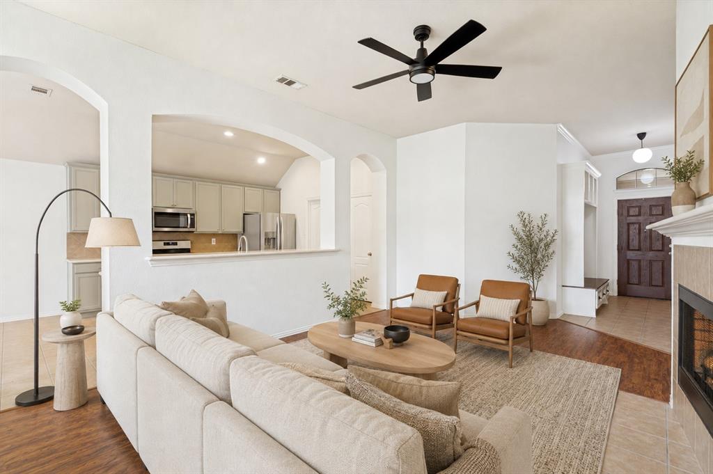 1316 Mountain Air Trail Fort Worth, TX 76131 - Photo 4 of 23 Wood-finish flooring throughout, featuring a living area with a ceiling fan, fireplace with a tile surround, and arched wall openings