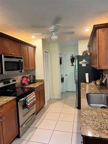 a kitchen with stainless steel appliances kitchen island granite countertop a refrigerator and a sink