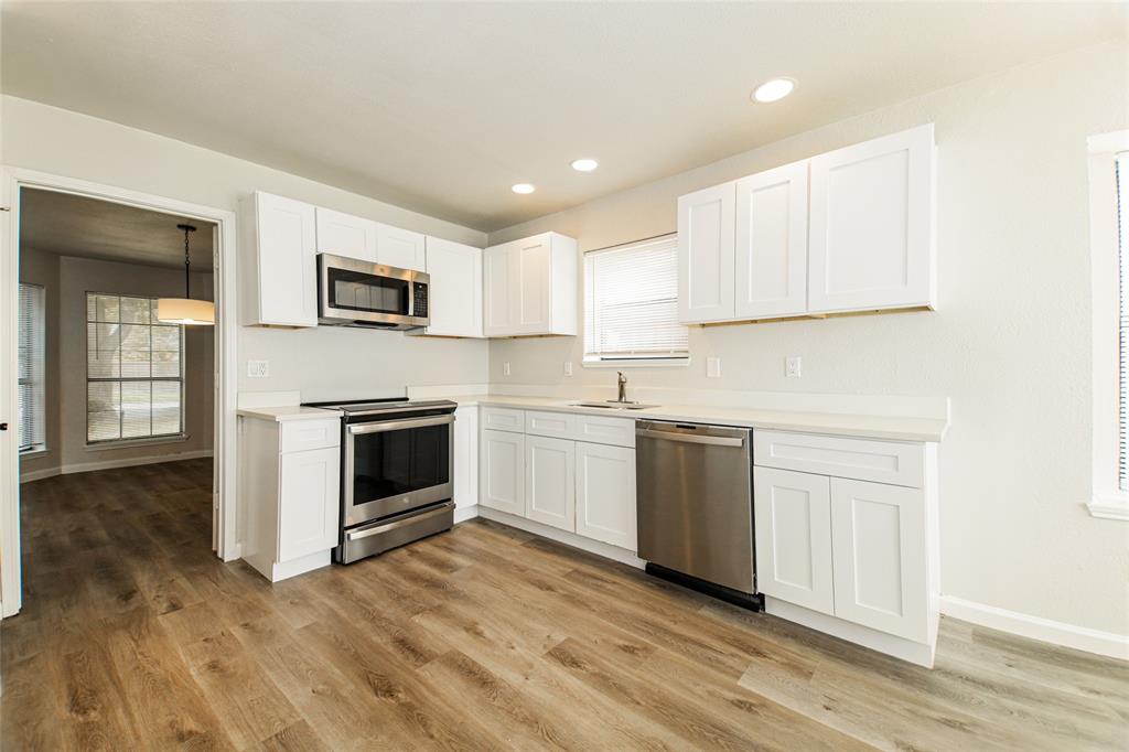 813 Ridgemont Drive Allen, TX 75002 - Photo 13 of 27 Kitchen with stainless steel appliances, white cabinetry, light wood-style floors, light countertops, and recessed lighting