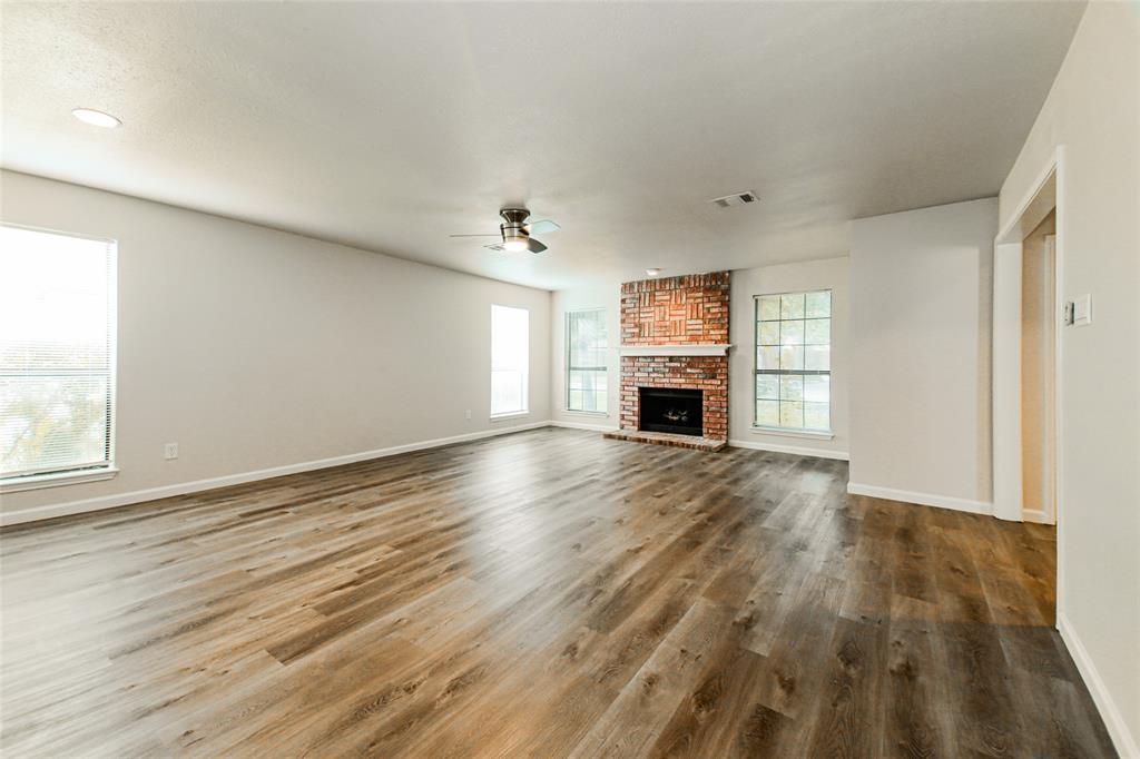 813 Ridgemont Drive Allen, TX 75002 - Photo 14 of 27 Unfurnished living room featuring a ceiling fan, plenty of natural light, wood finished floors, and a brick fireplace