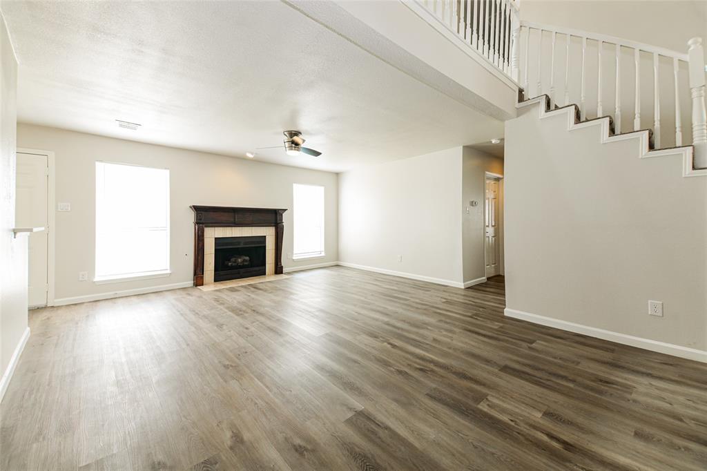 813 Ridgemont Drive Allen, TX 75002 - Photo 4 of 27 Unfurnished living room featuring a ceiling fan, dark wood-style floors, a tiled fireplace, and stairway