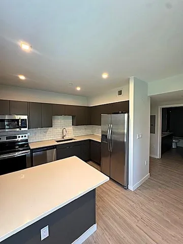 a large kitchen with stainless steel appliances a refrigerator and a stove top oven