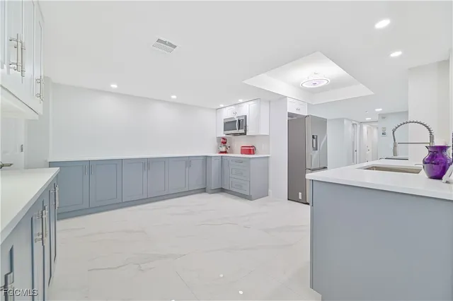 a large white kitchen with a sink and cabinets