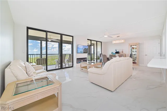 a living room with furniture large windows a flat screen tv and a view of bedroom