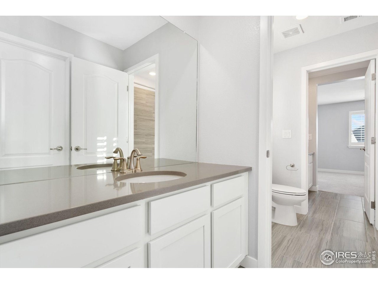 2883 Storm View Court Timnath, CO 80547 - Photo 26 of 36 a bathroom with a sink a toilet and a large mirror