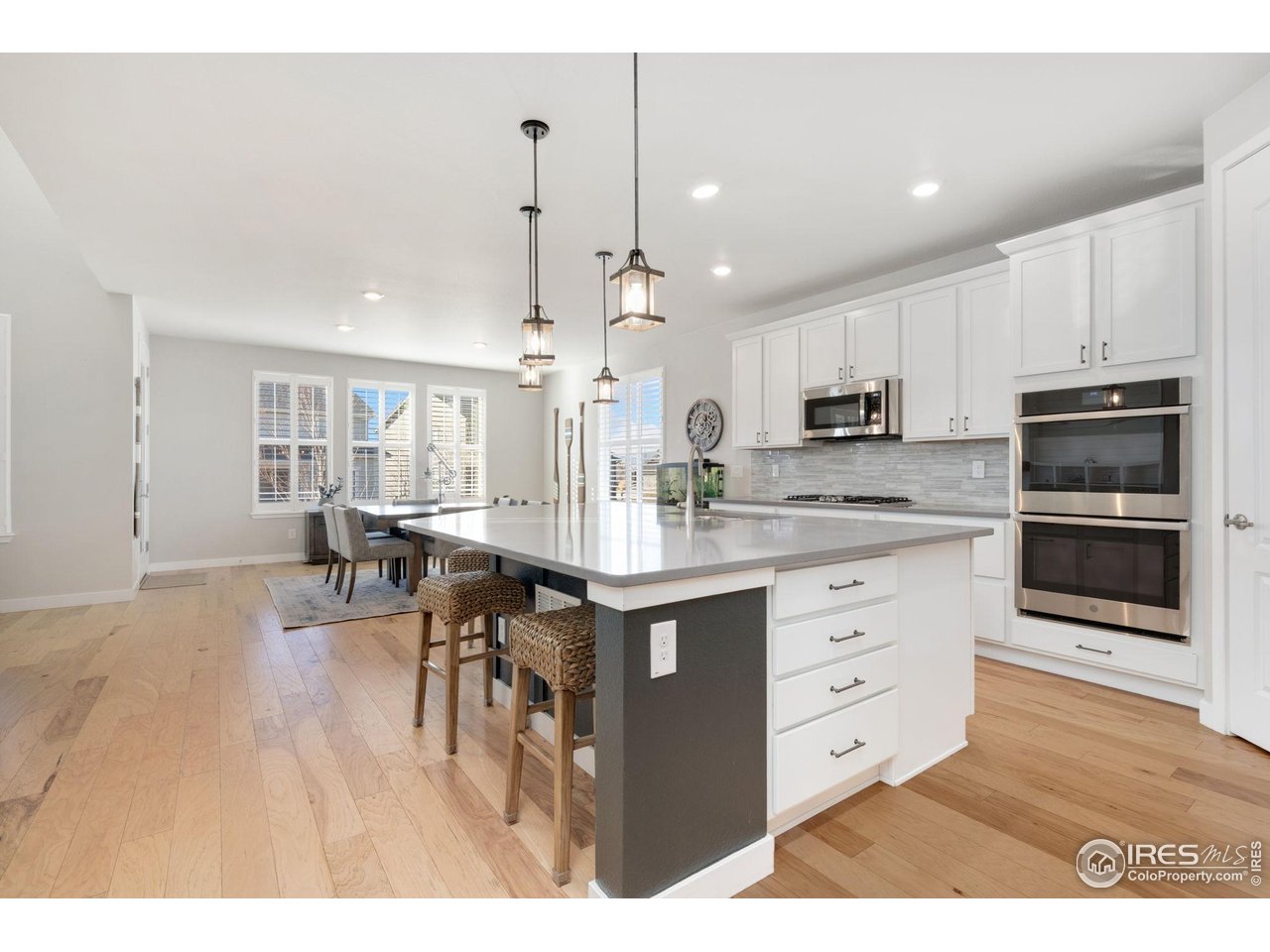 2883 Storm View Court Timnath, CO 80547 - Photo 6 of 36 a kitchen with kitchen island granite countertop a stove a sink a dining table and chairs with wooden floor