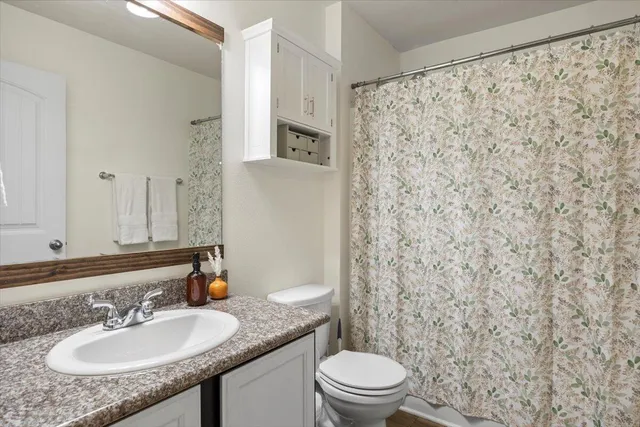 a bathroom with a granite countertop sink a toilet and a mirror