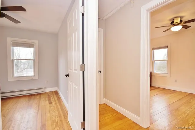 a view of an empty room with a window and wooden floor