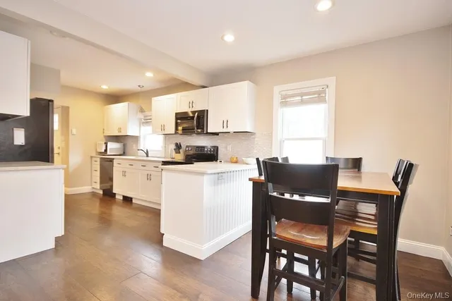 a living room with stainless steel appliances kitchen island granite countertop a dining table chairs and a refrigerator