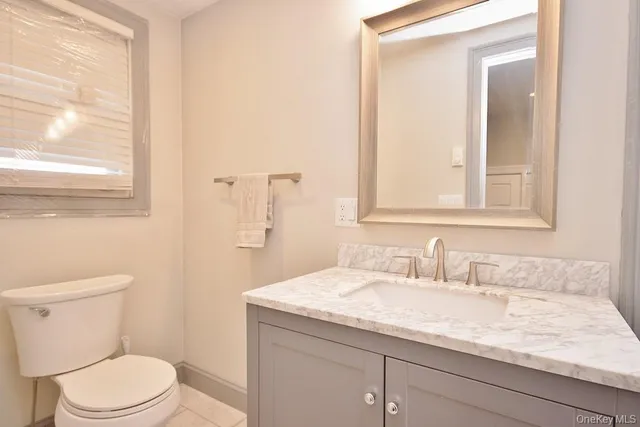 a bathroom with a granite countertop sink a toilet and a mirror
