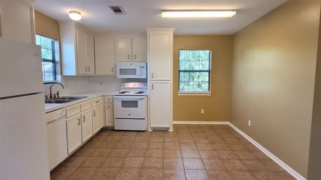 a kitchen with white cabinets and white appliances