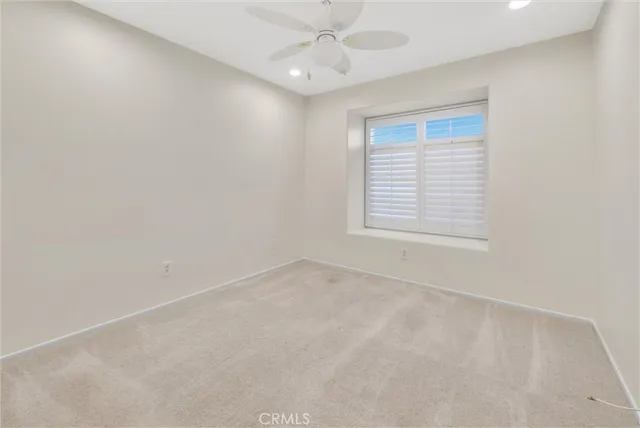 an empty room with a window and a ceiling fan