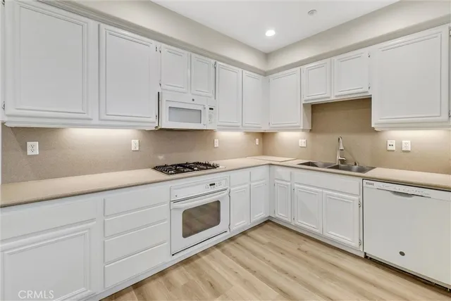 a kitchen with granite countertop white cabinets and white appliances