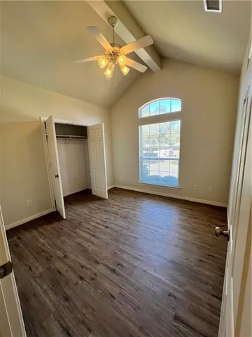 an empty room with wooden floor chandelier fan and windows
