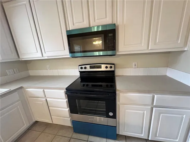 a kitchen with white cabinets and stainless steel appliances