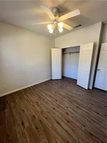 an empty room with wooden floor and fan