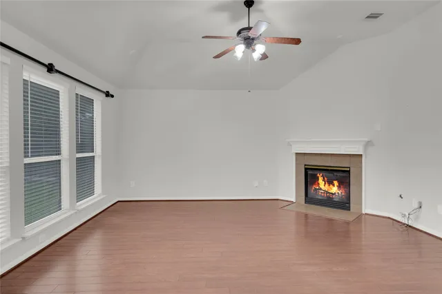 an empty room with wooden floor chandelier and windows