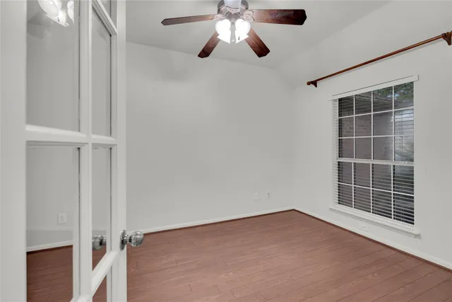 a view of empty room with wooden floor and fan